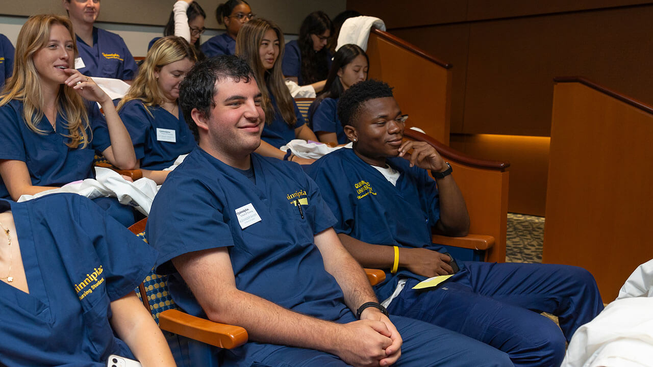 nursing students sit in rows wearing their scrubs