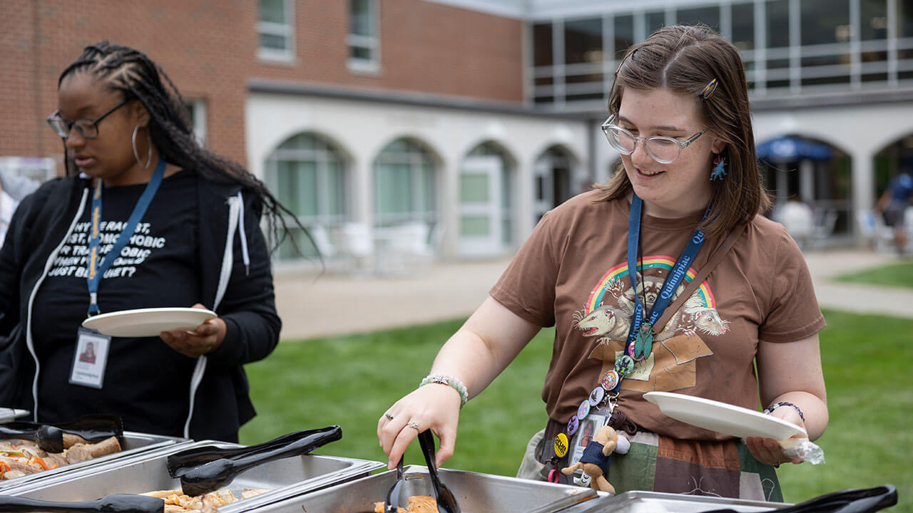 Student using tongs to pick up food from buffet