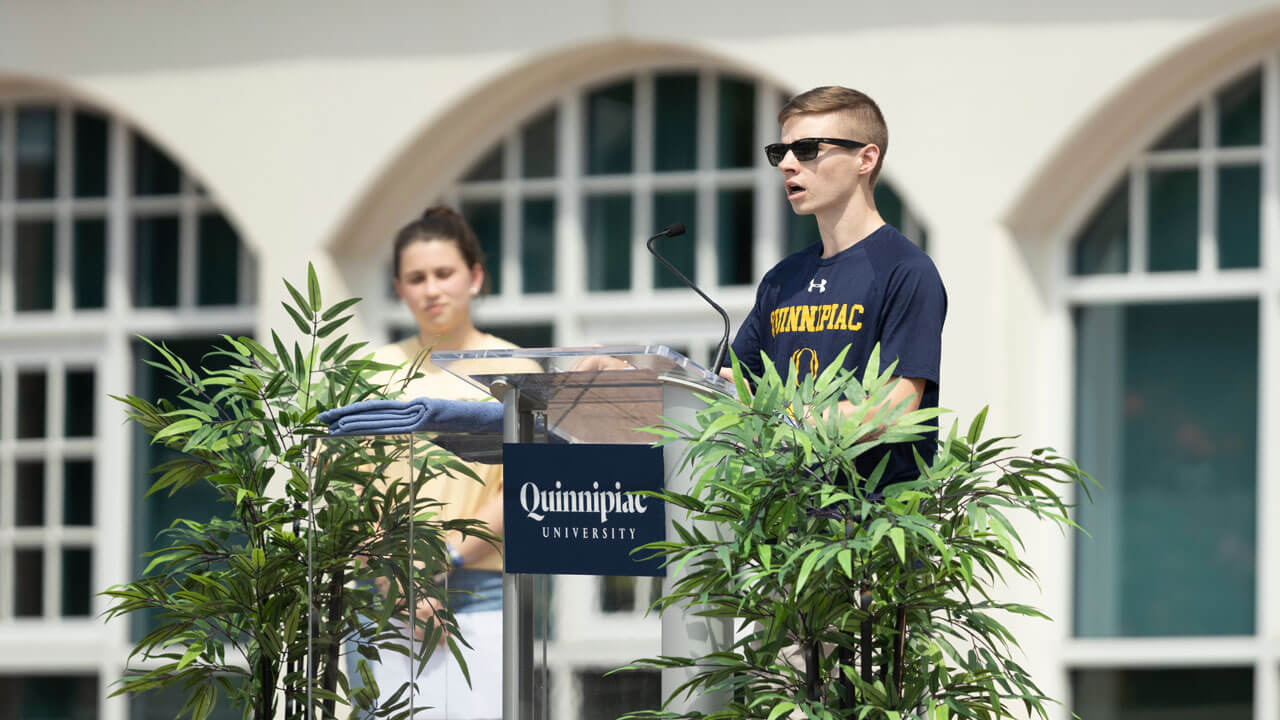 Quinnipiac student John Shepherd addresses new students from the library steps