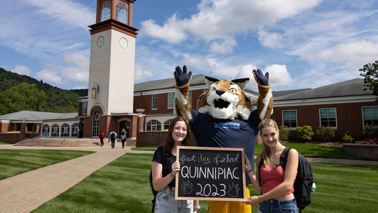 Two students pose with Boomer in front of the clocktower