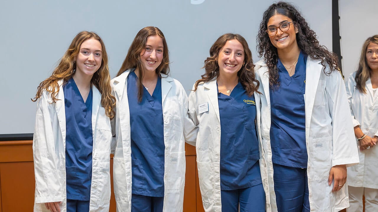 four nursing students smile for their photo to be taken