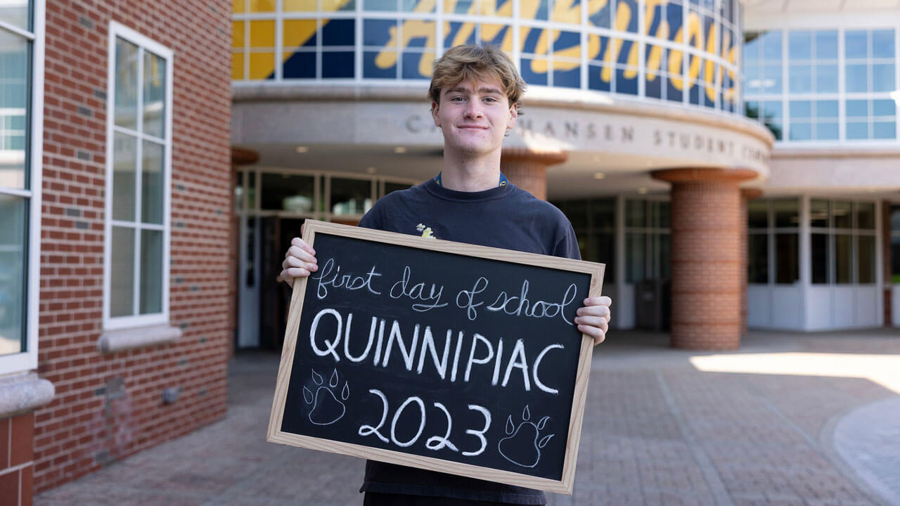 Student takes a photo with a sign