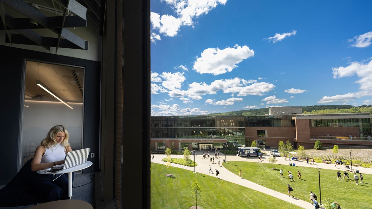 Student sits in window looking out at the view of the South Quad Festivities