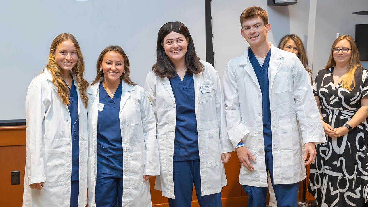 four nursing students smile as they pose for their photo to be taken