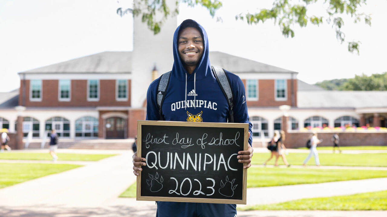 Student poses with a sign on the first day of classes