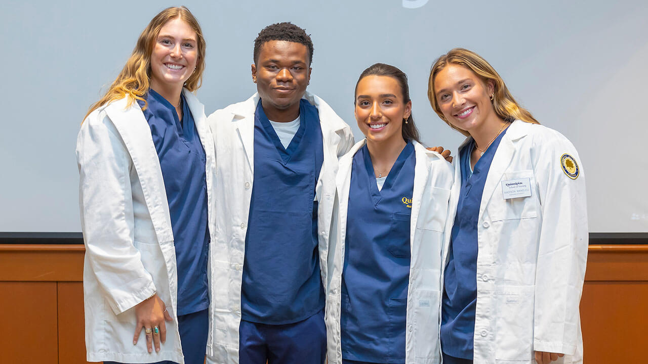 four nursing students pose in their white coats