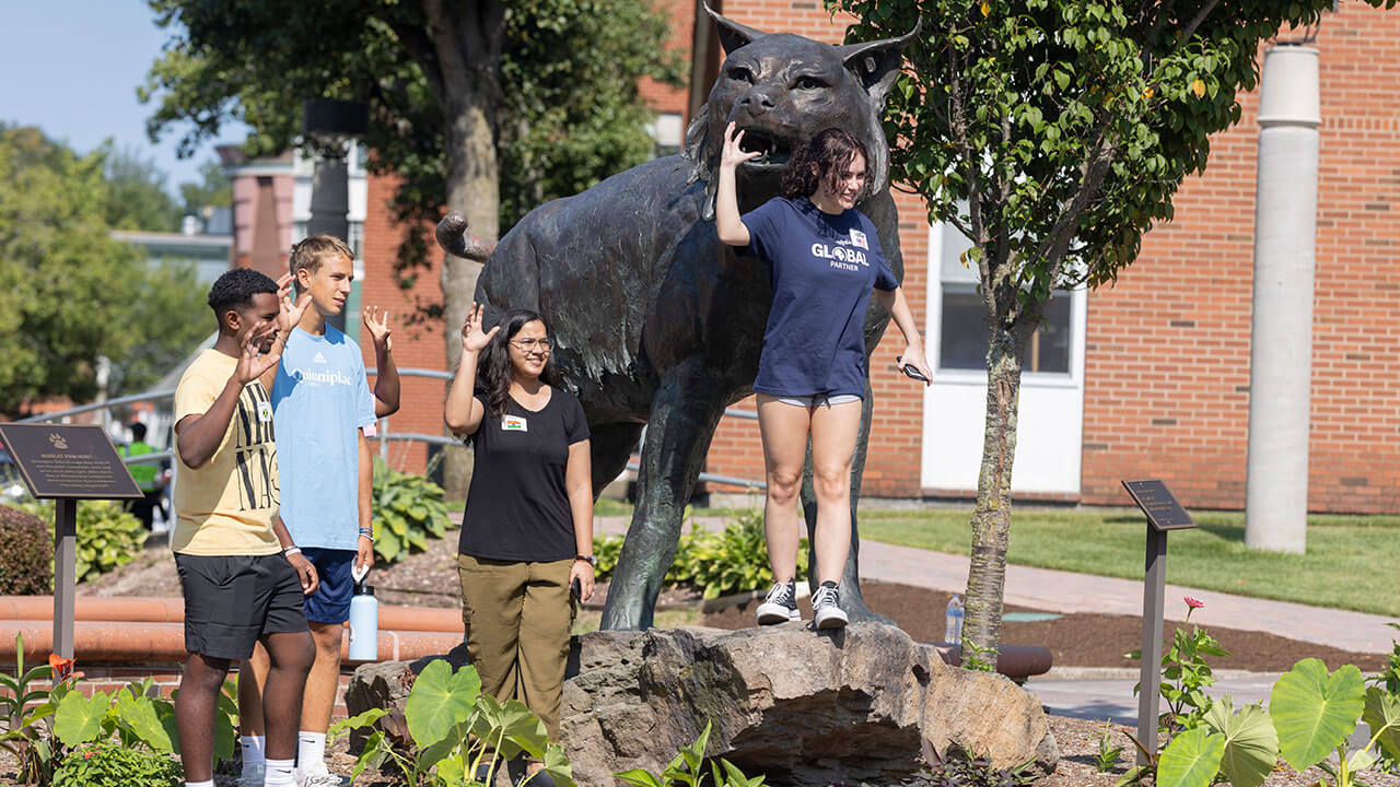 International students stand by the Bobcat statue