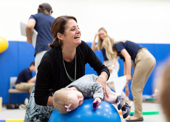 professor of occupational therapy valerie strange plays with baby on blue workout ball