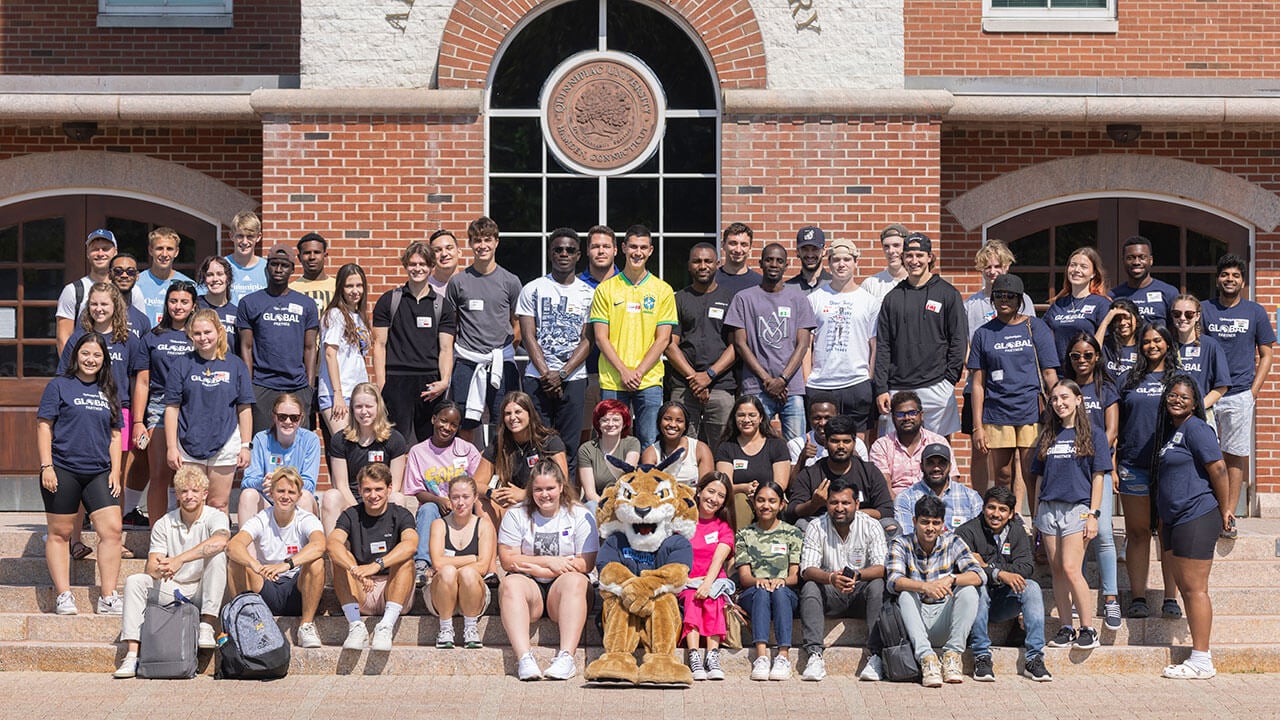A group of international students take a photo with Boomer the Bobcat
