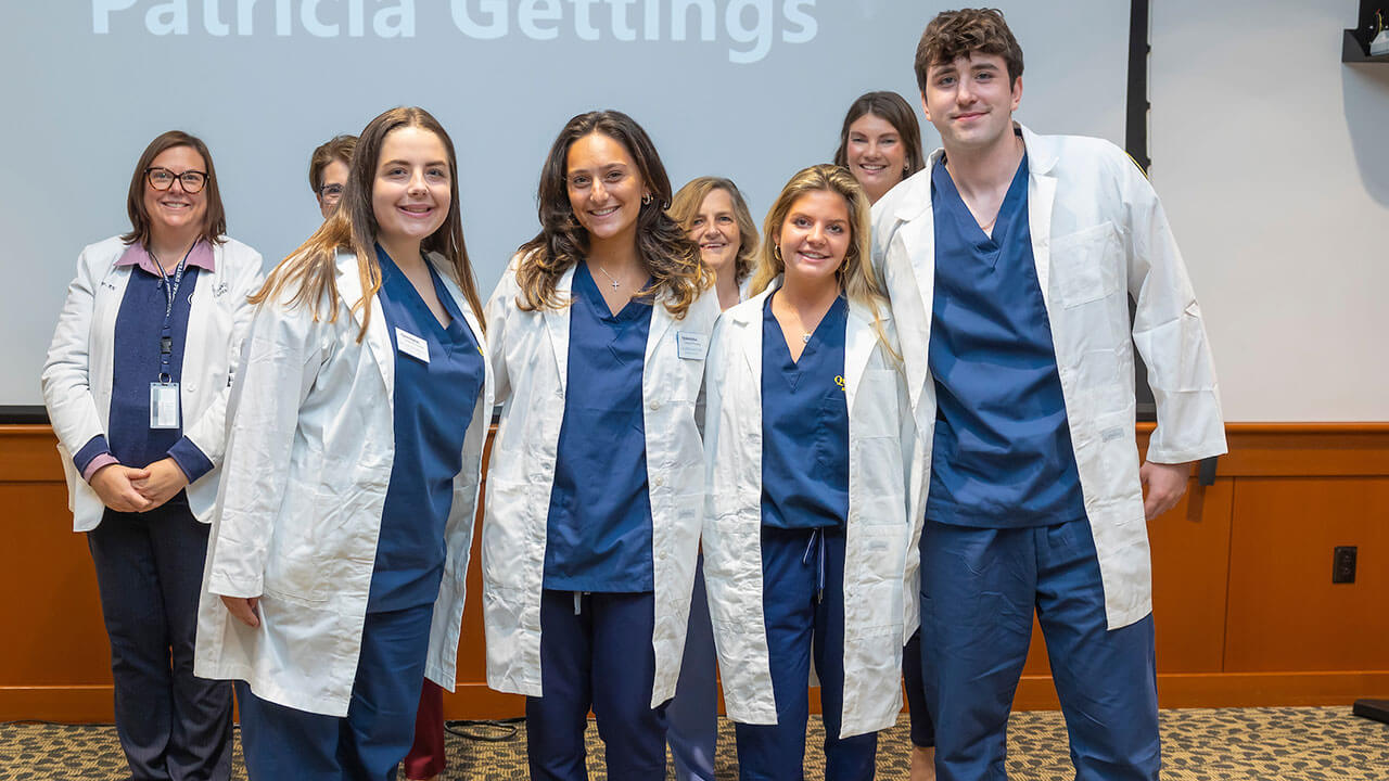 four nursing students pose together in their new white coats