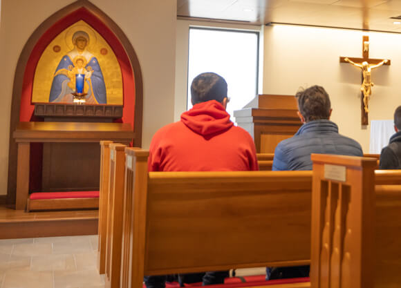 Two students sit in a service in the Catholic chapel at Quinnipiac