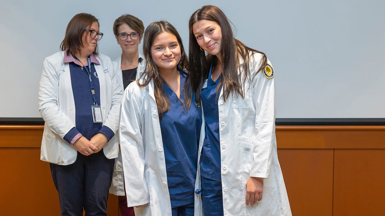 two nursing students pose together wearing their new white coats