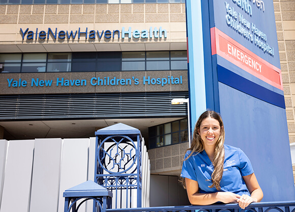 Melissa Guzman smiles proudly in her scrubs outside of Yale New Have Children's Hospital