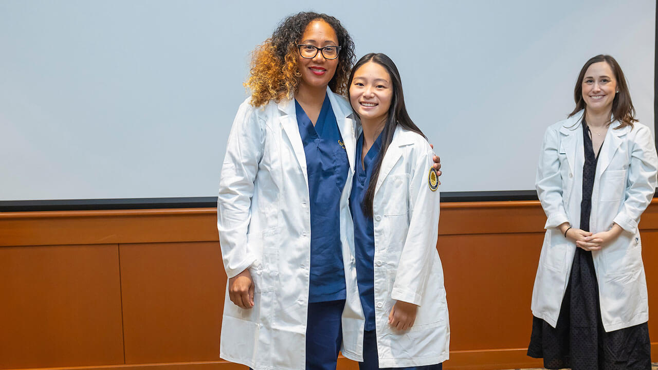 two nursing students pose together in their brand new white coats