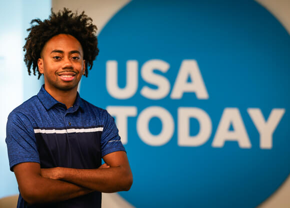 Toyloy Brown smiles in front of a USA Today sign
