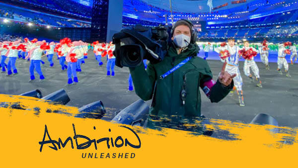 Matt Andrews holds a camera on his shoulder while in an olympic stadium in Beijing