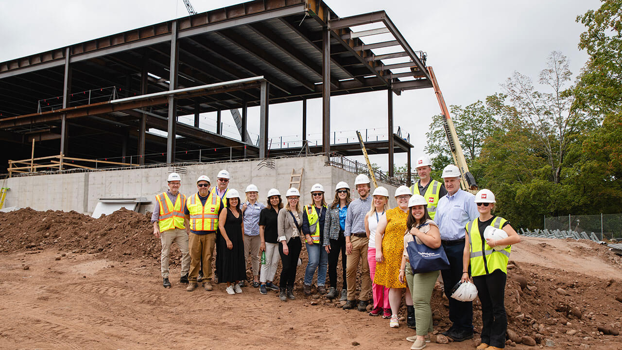 Faculty and staff smiling in front of the construction site