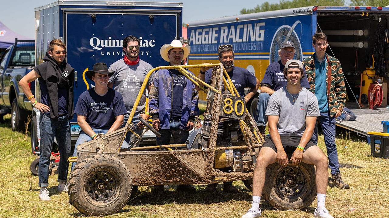 QU Baja team engineering students pose for a picture with their winning Baja vehicle