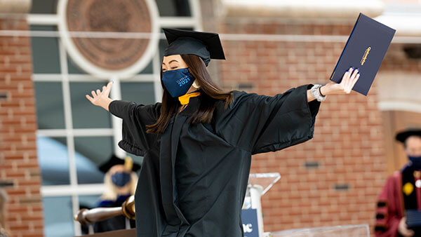 A student in receives their diploma at commencement with excitement