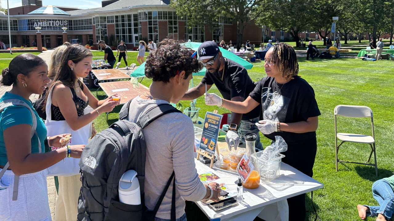 Many students stand by Entrepreneur's table