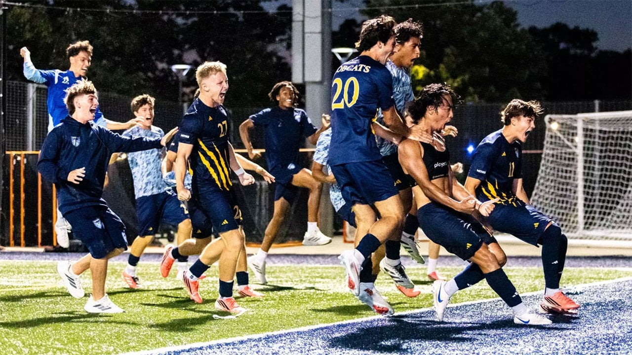 The mens soccer team jump across the field in celebration.