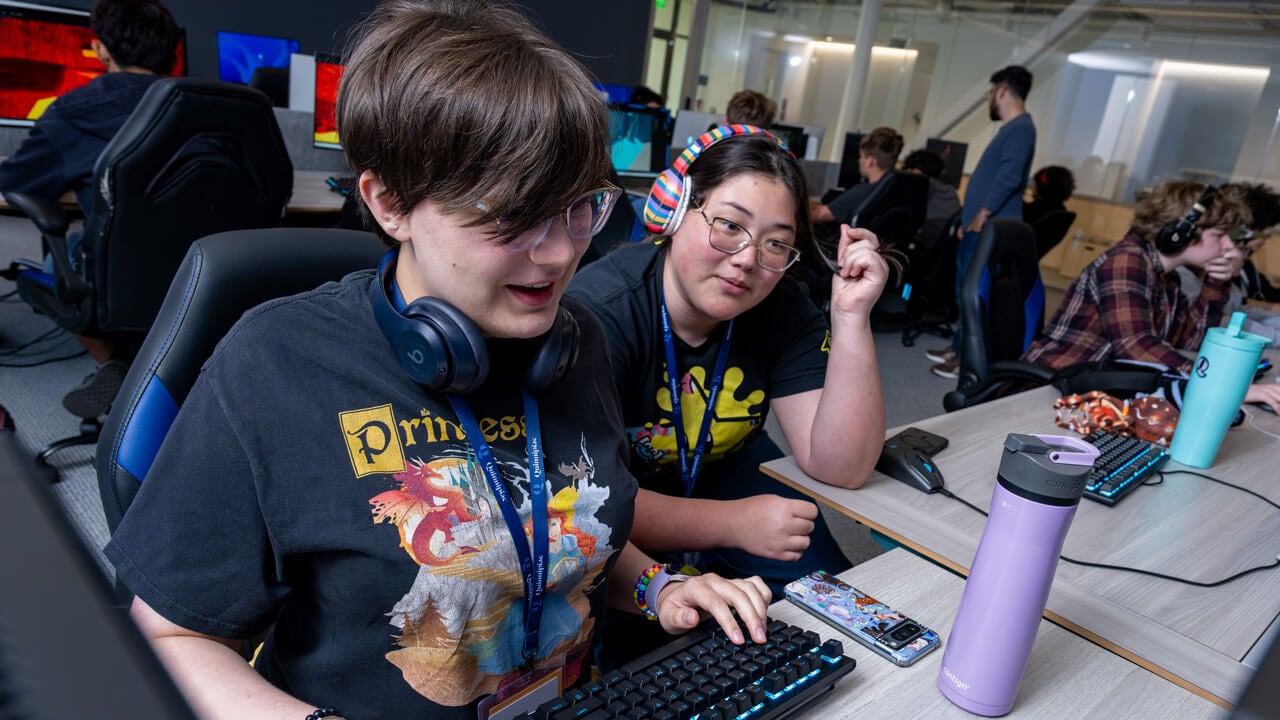 Two students sitting together close to a keyboard.