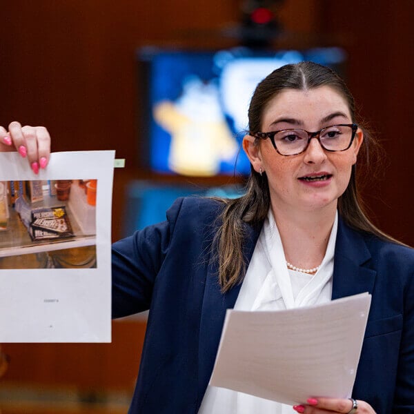 A female law student in a blazer holding up a sheet of paper.