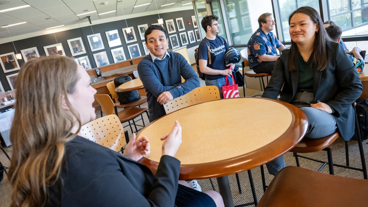 A small group of students smiling casually around a table in the Law Student Lounge.