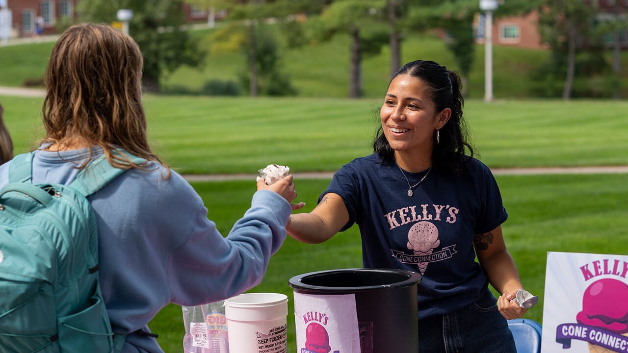 Kelly's Cone Connection staff member handing out ice cream while smiling