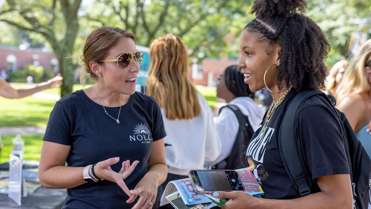 A student has a conversation with a business owner during a local business pop-up event on the Quad