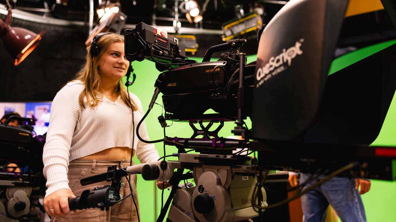 Student controls a camera in the McMahon Center production room.