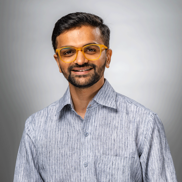 Aman Desai smiling against a grey background