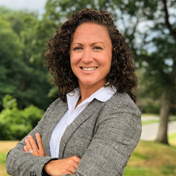 Jenna Curren posing with her arms crossed against some greenery