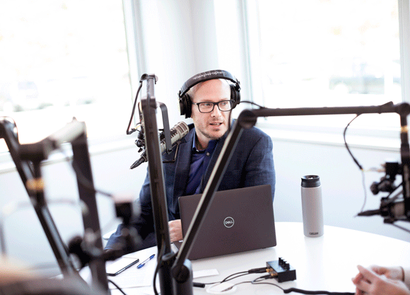 Individual with headphones on talking in the podcast studio