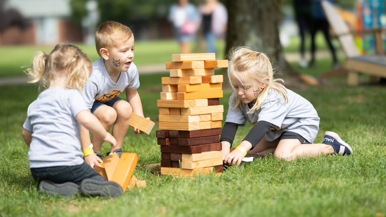 A group of little kids play Jenga at Bobcat Weekend.