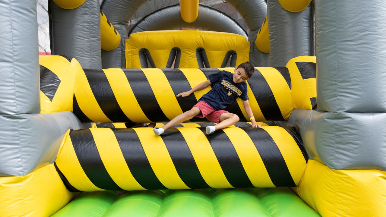 A little boy playing in the bouncy house at Bobcat Weekend.