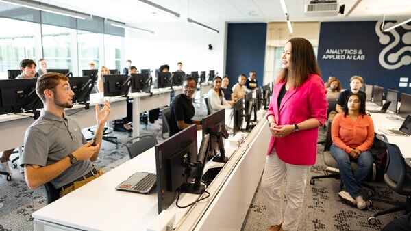 Dozens of students and professor talk in the Applied Analytics and AI Lab classroom