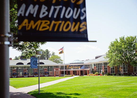 A view of the Mount Carmel Campus Quad with a branded ambition flag hanging
