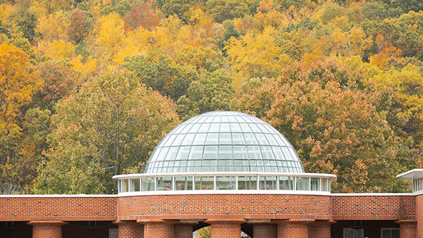Quinnipiac School of Business Center with the fall foliage of Sleeping Giant State Park behind it