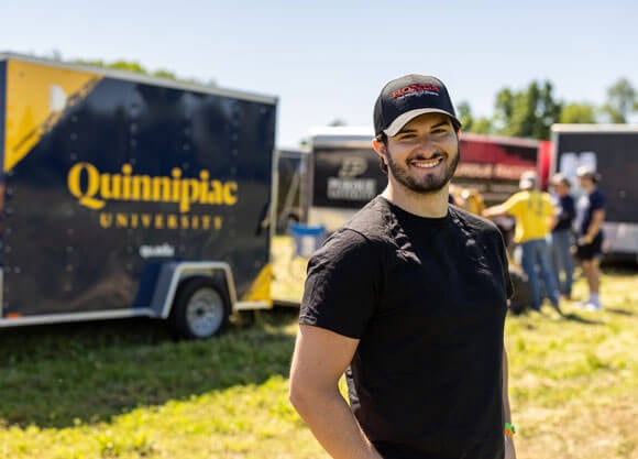 Alex Petrarca stands in front of a Quinnipiac truck at the intercollegiate design competition with the BAJA team.
