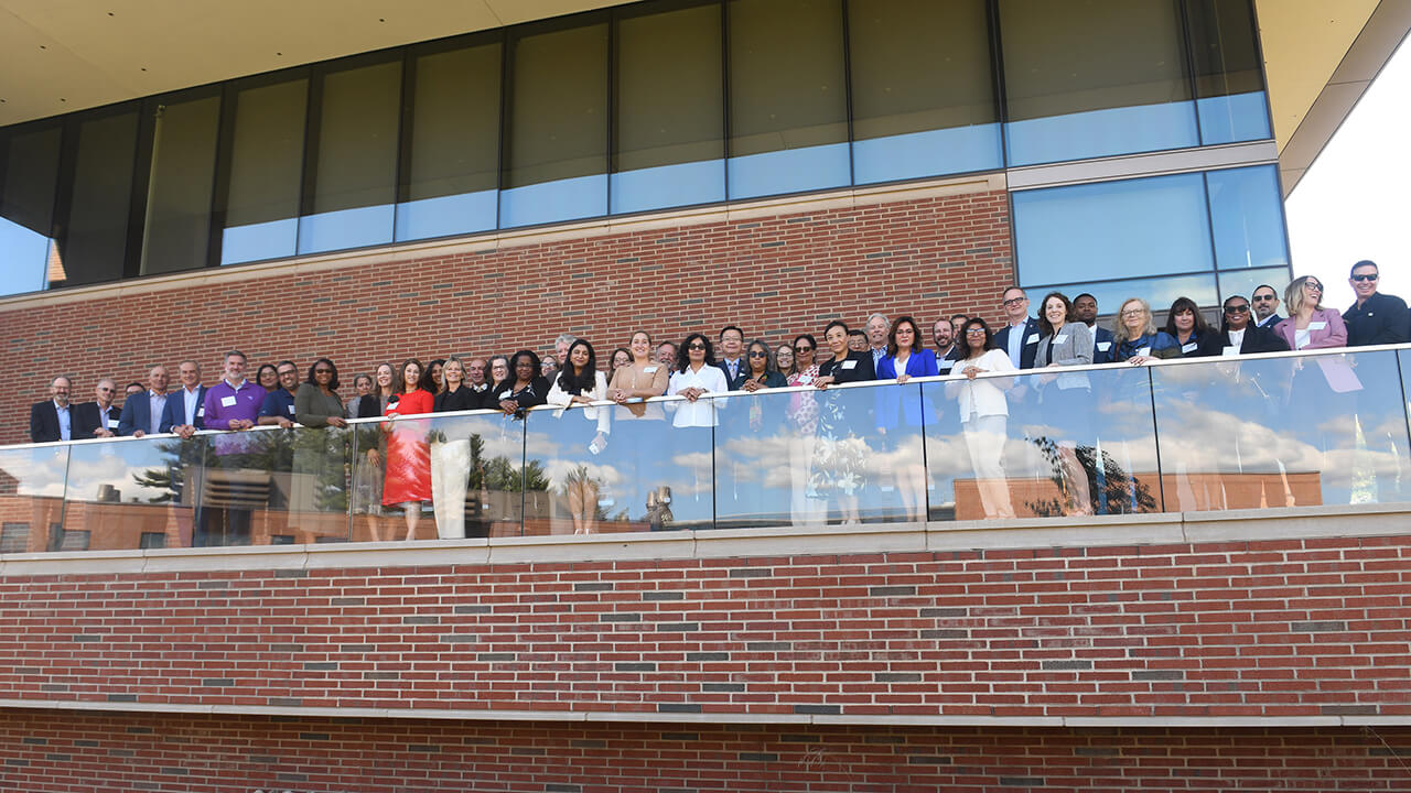 Group of people look over balcony to smile for a photo