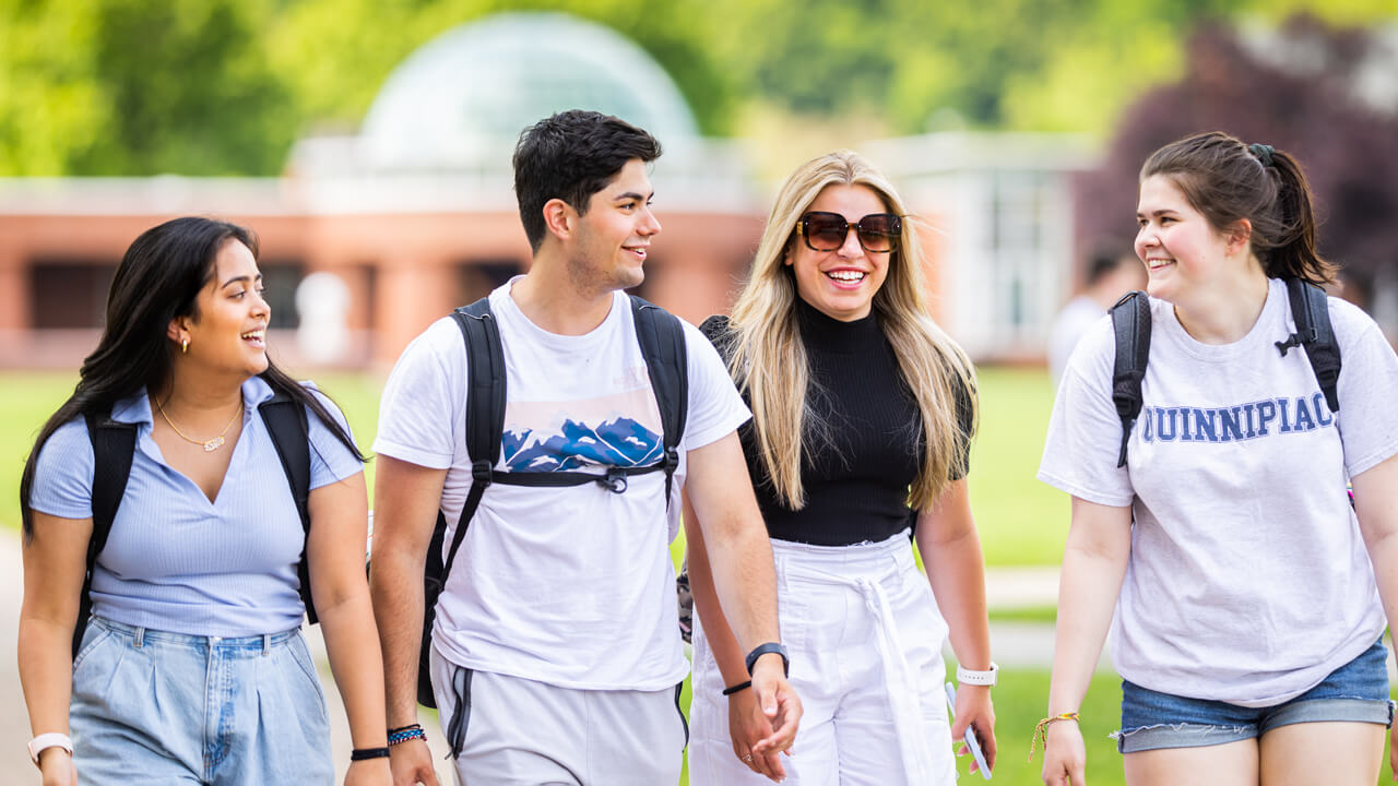 Four students walk together on the Quad