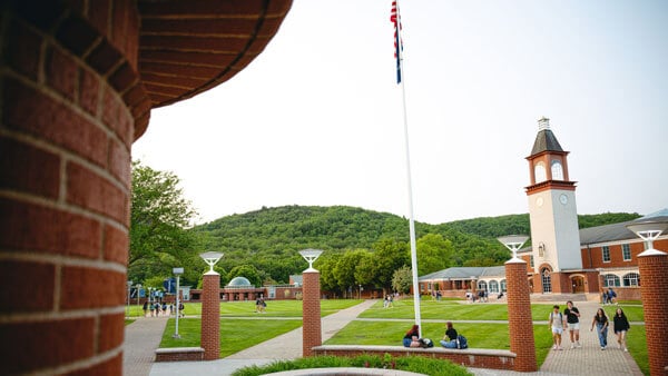 Student walk across the Mount Carmel Campus Quad with the Arnold Bernhard Library clock tower in the background.
