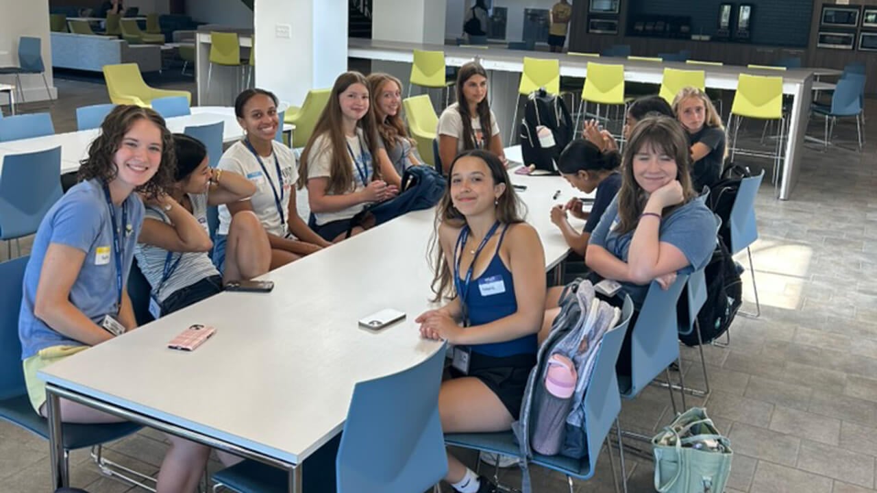 A group of 11 female students sitting together around a table in the North Haven cafeteria.