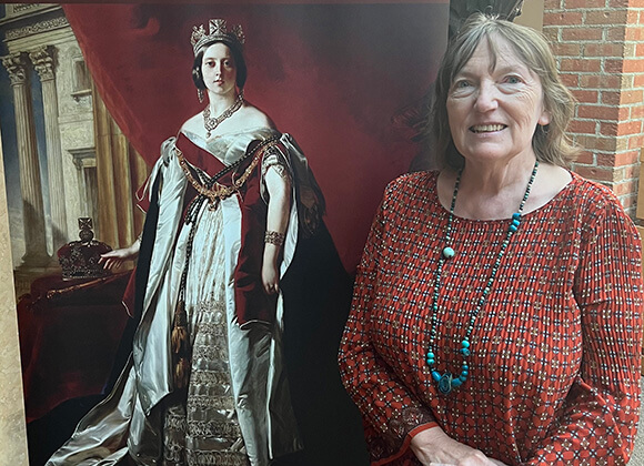 Christine standing next to a poster of Queen Elizabeth for the exhibit poster.