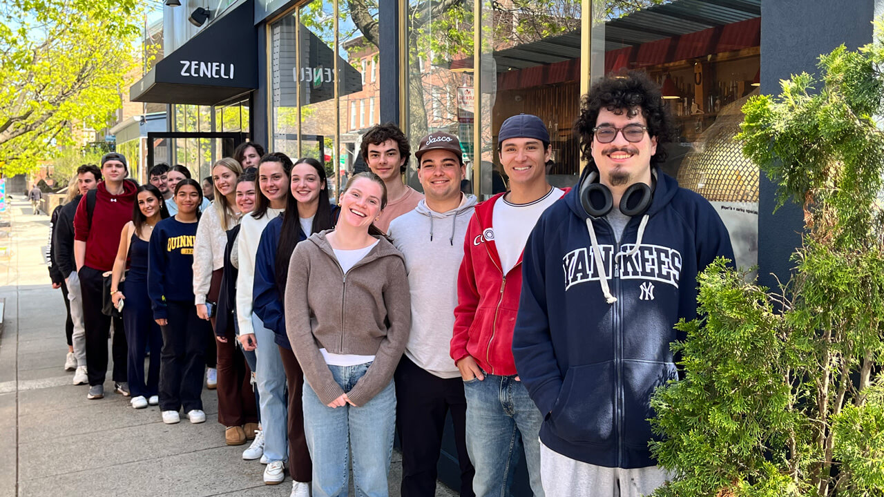 A group shot of the students standing outside in a line under the Zeneli awning.