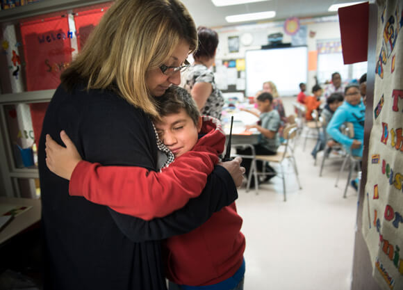 Grade school student hugging teacher