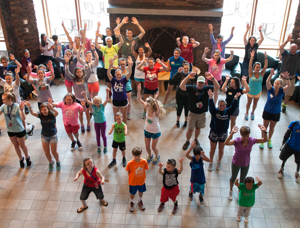 Dozens of campers with limp differences raise their hands during a team building exercise