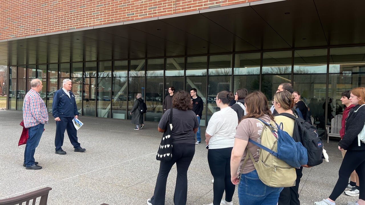 The students, professor and Facilities member standing outside the glass windows of The SITE before their tour.