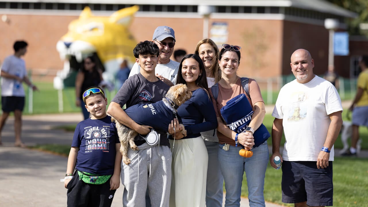 A family in Quinnipiac gear pose for a photo on the quad during Bobcat Weekend